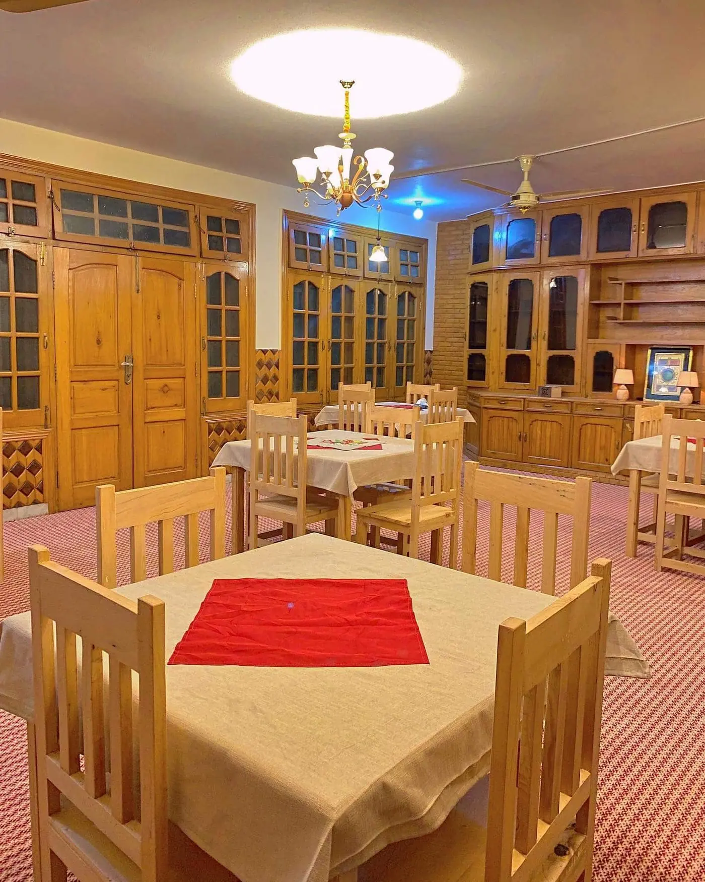 The dining hall with wooden cabinets, laid tables and a chandelier