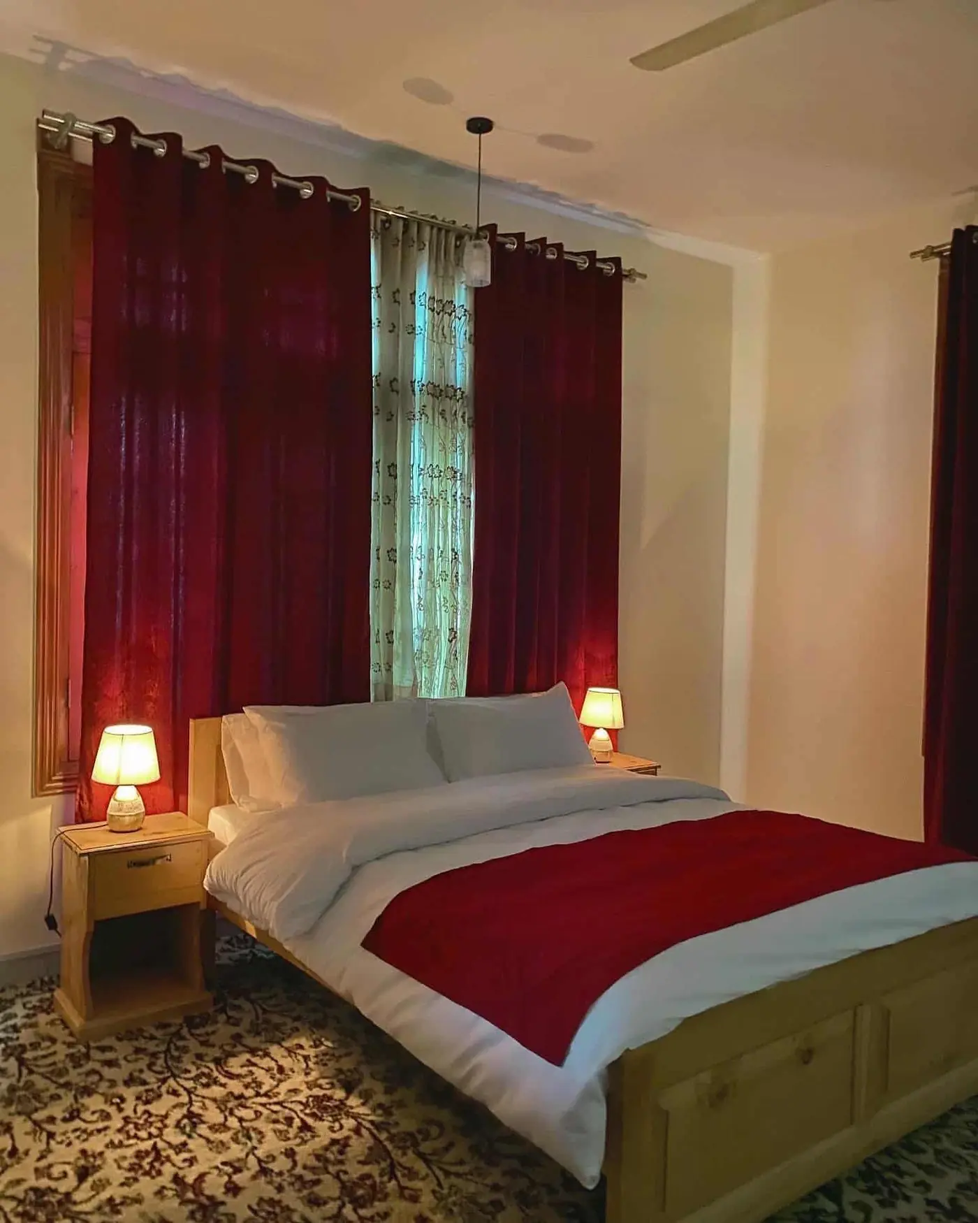 Deluxe bedroom with deep red curtains and bedside lamps