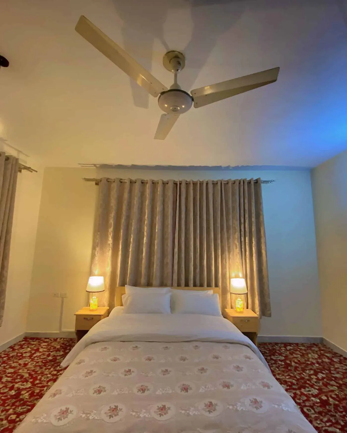 Twin and single bedroom with soft lighting and warm curtains